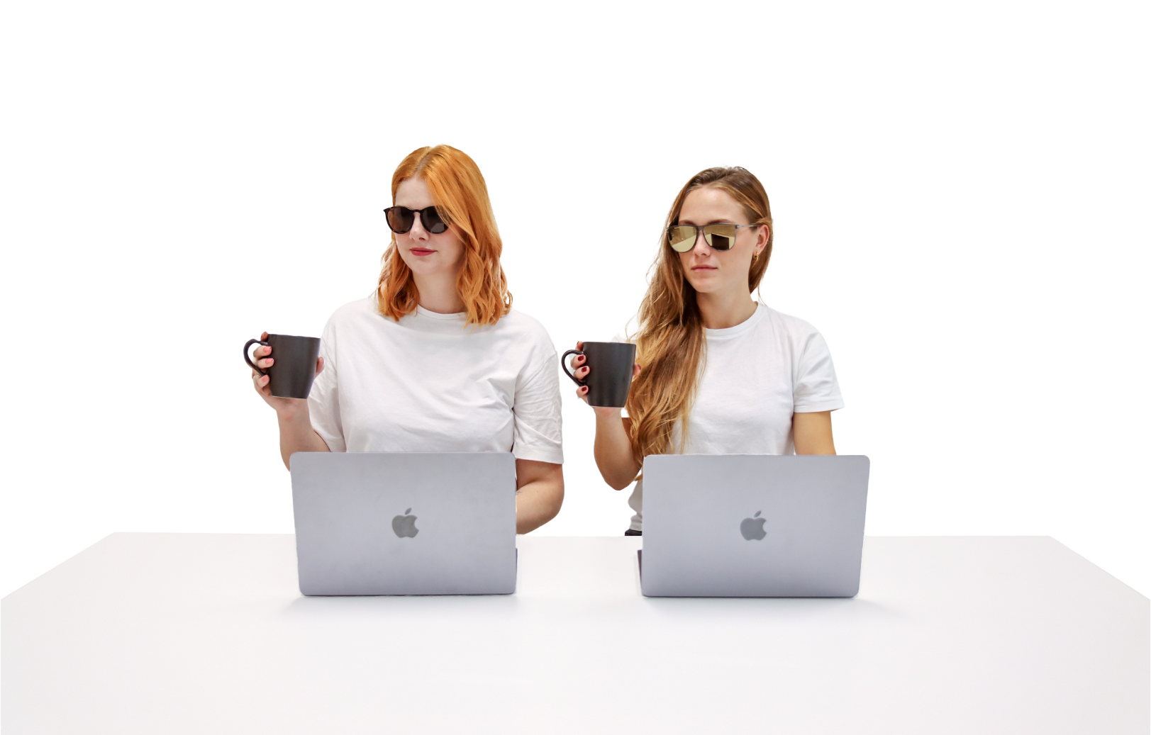 Bild von zwei Personen die an einem Computer arbeiten und dabei mit einer Kaffeetasse in der Hand in die selbe Richtung schauen